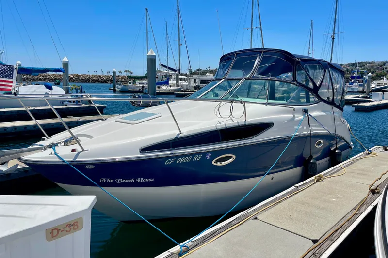 2008 Bayliner 265 boat docked at marina, featuring sleek design and blue accents.