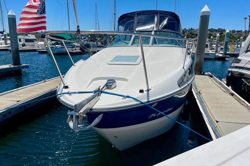 2008 Bayliner 265 boat docked at marina with American flag, clear blue sky.