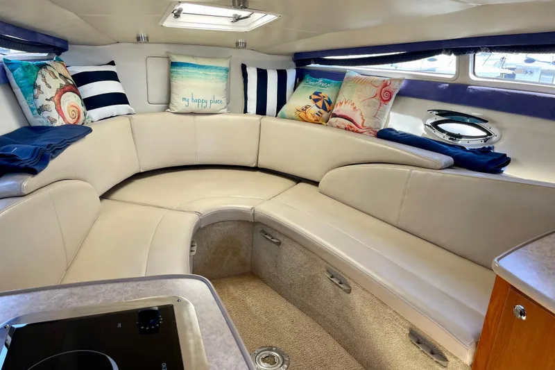 Interior of 2008 Bayliner 265 boat with cozy seating and decorative pillows.