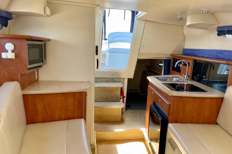 2008 Bayliner 265 interior with kitchenette, seating, and stairs to deck.