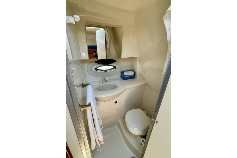 Compact bathroom in 2008 Bayliner 265 boat, featuring sink, toilet, and mirror.