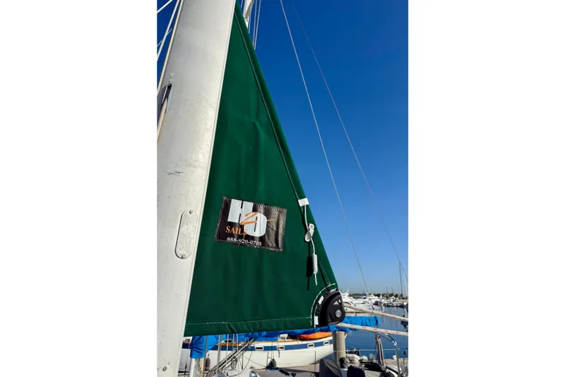 Green sail on a 2001 Beneteau 411 yacht against a clear blue sky.