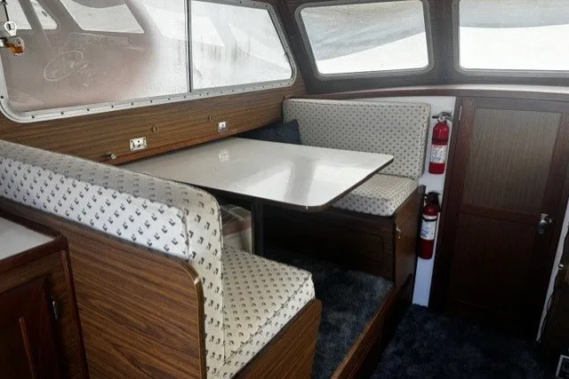 1972 Luhrs 32 Convertible boat interior with dining area, wood paneling, and fire extinguishers.