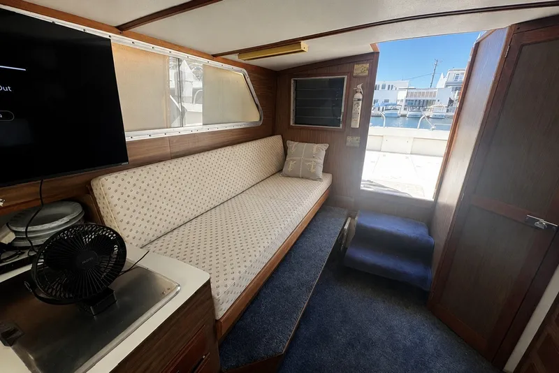 Interior of a 1972 Luhrs 32 Convertible boat with sofa, TV, and marina view.