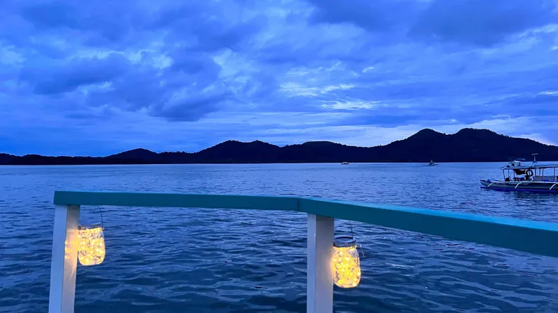 Phinisi Custom Pleasure Cruiser 2016 on serene waters at dusk with illuminated lanterns.