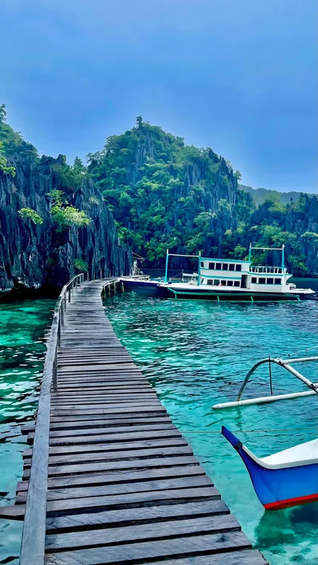 Wooden dock leading to a Phinisi Custom Pleasure Cruiser or Dive Boat, 2016, in a tropical bay.