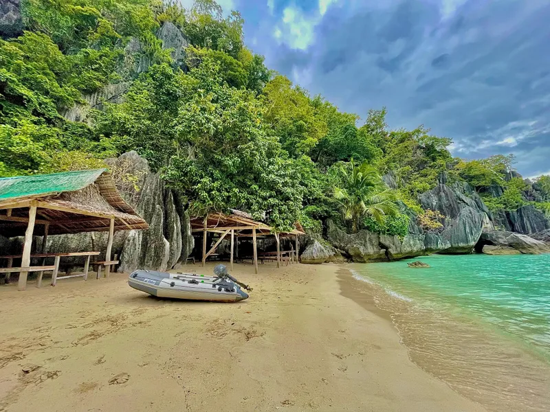 Tropical beach with lush greenery, wooden huts, and a Phinisi Custom Pleasure Cruiser or Dive Boat, 2016.