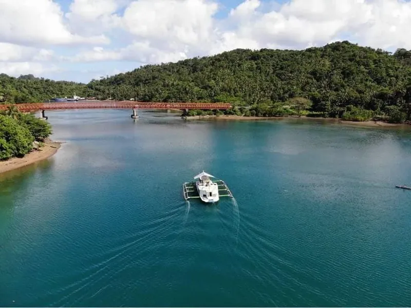 Phinisi Custom Pleasure Cruiser 2016 on serene river with lush green hills and bridge.