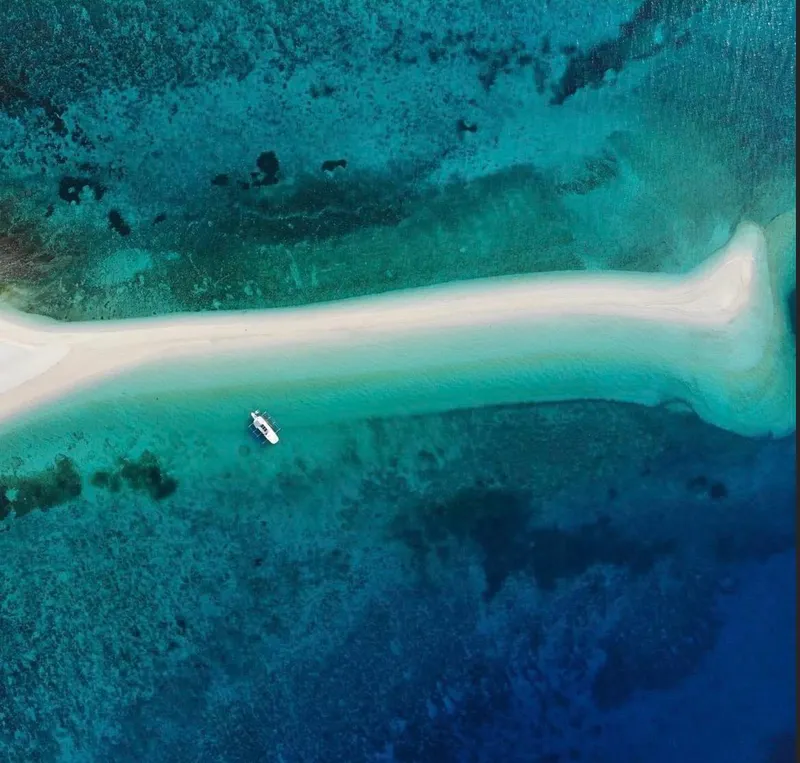 Aerial view of a 2016 Phinisi Custom Pleasure Cruiser near a sandbar in turquoise waters.