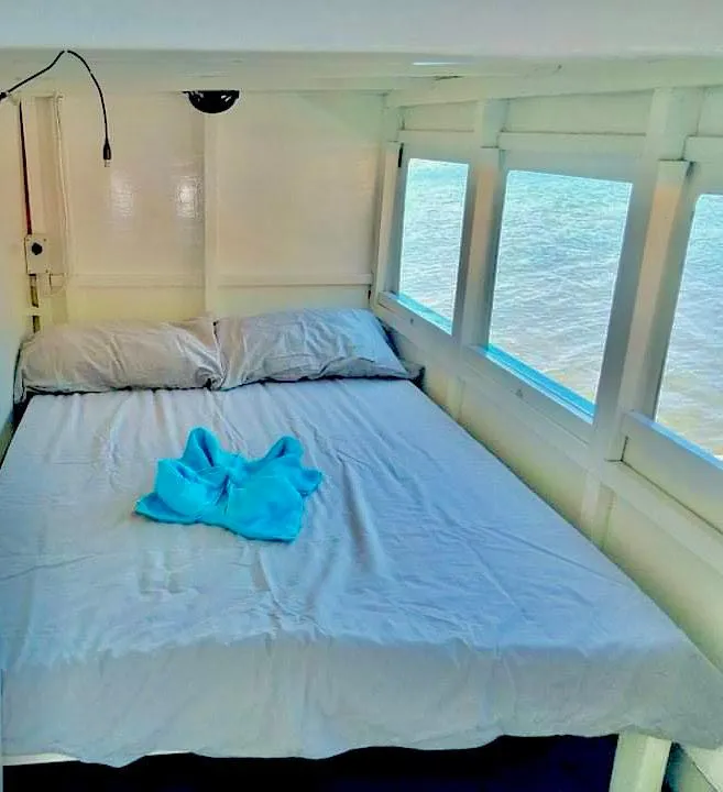 Cozy bedroom on a 2016 Phinisi Custom Pleasure Cruiser with ocean view.