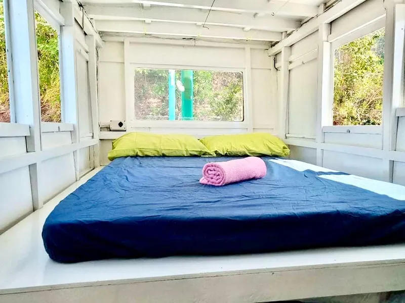 Cozy cabin bedroom on 2016 Phinisi Custom Pleasure Cruiser with blue bedding and green pillows.