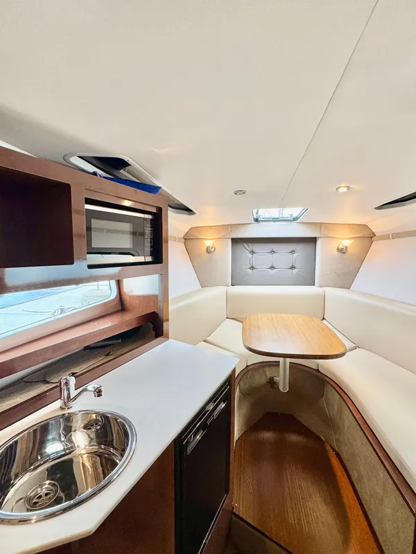 2016 Four Winns 255 Vista cabin interior with kitchenette, seating, and table.