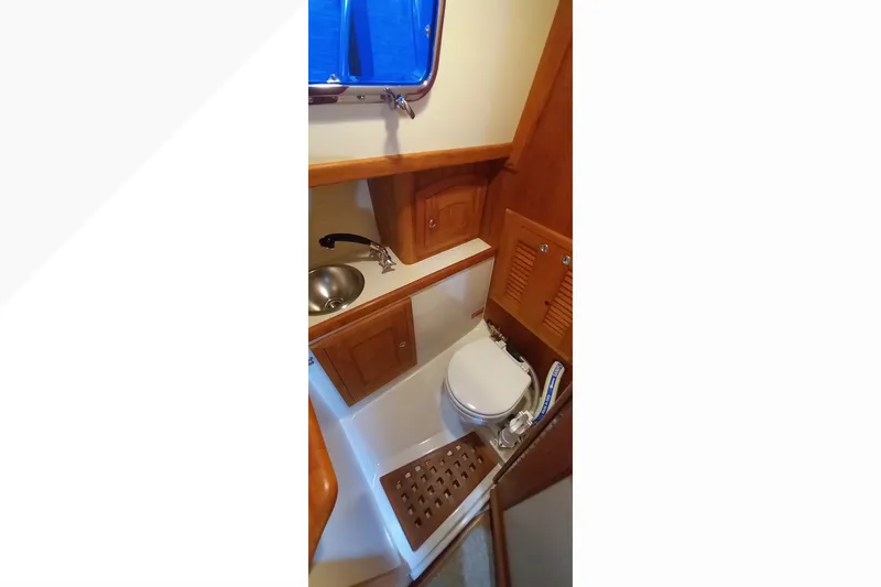 Interior of 2002 Pacific Seacraft Dana 24, featuring compact marine bathroom with wooden cabinetry.