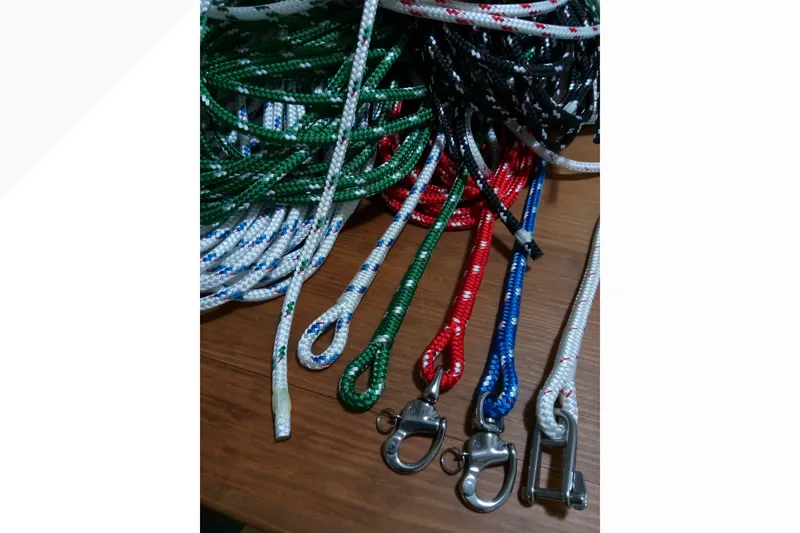 Colorful sailing ropes and hardware for a 2002 Pacific Seacraft Dana 24 on wooden surface.