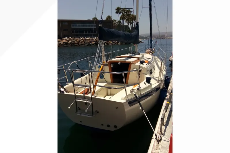 2002 Pacific Seacraft Dana 24 sailboat docked in a sunny marina.