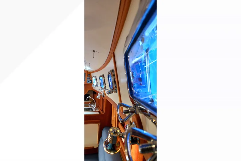 Interior view of 2002 Pacific Seacraft Dana 24 sailboat, showcasing portholes and wooden finish.