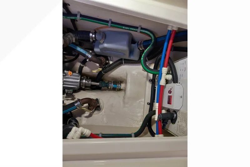 Engine compartment of a 2002 Pacific Seacraft Dana 24 sailboat, showcasing hoses and mechanical components.