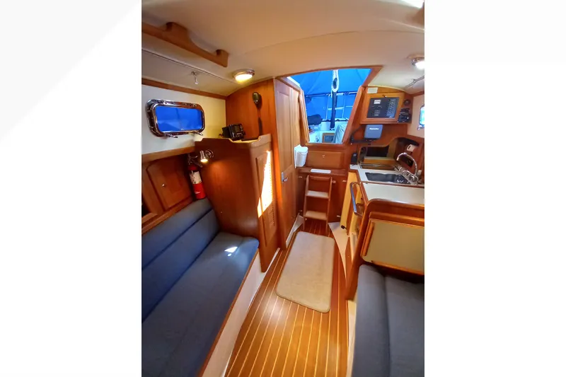 Interior of 2002 Pacific Seacraft Dana 24 sailboat, featuring cozy seating and wooden finishes.