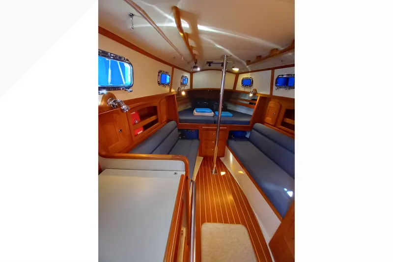 Interior of 2002 Pacific Seacraft Dana 24 sailboat with wooden finishes and blue seating.