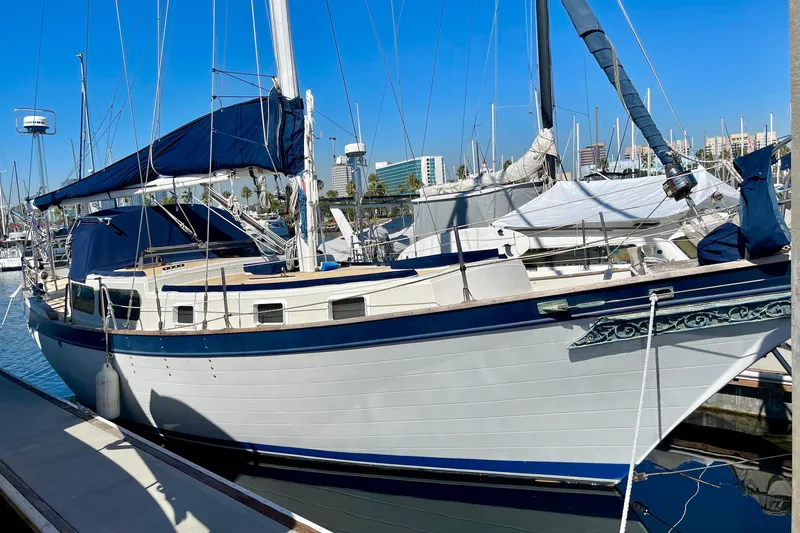 1978 Downeast 38 sailboat docked in a marina under clear blue skies.