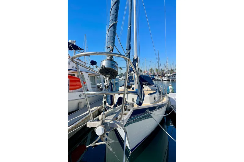 1978 Downeast 38 sailboat docked in marina, clear blue sky background.