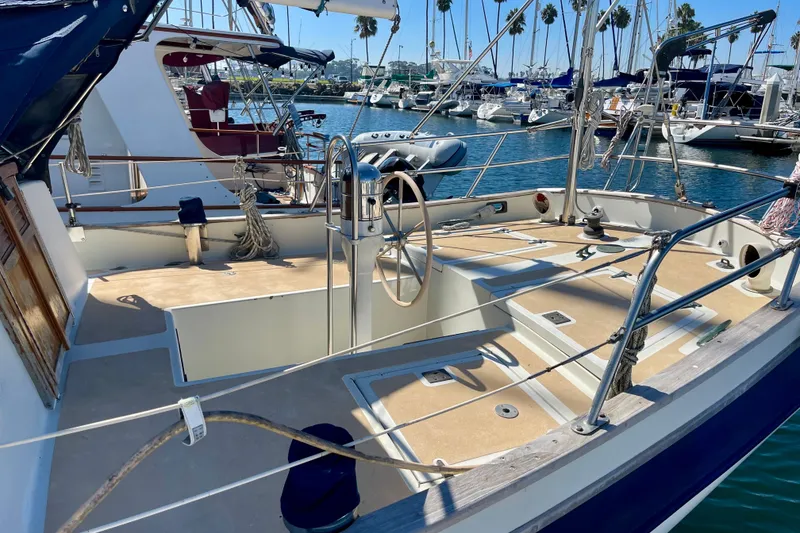 1978 Downeast 38 sailboat cockpit with steering wheel, docked in a marina.