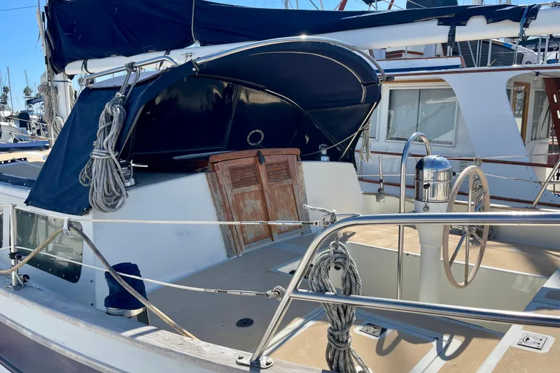 1978 Downeast 38 sailboat with blue canopy and wooden hatch in marina.