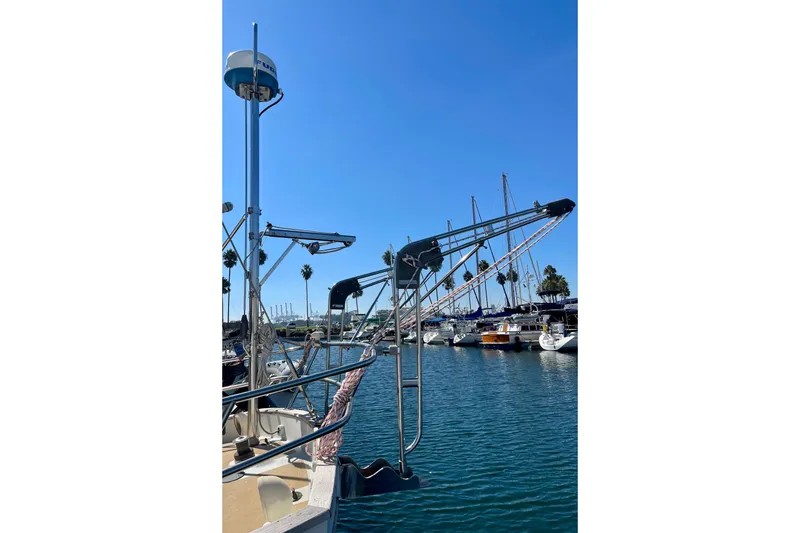 1978 Downeast 38 sailboat docked in a sunny marina with clear blue skies.