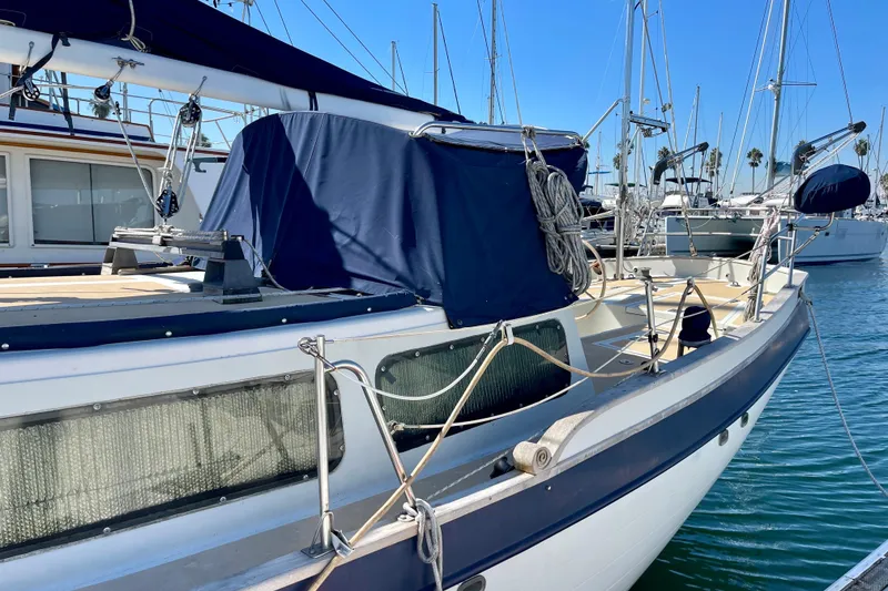1978 Downeast 38 sailboat docked in marina, featuring blue canvas covers and rigging.