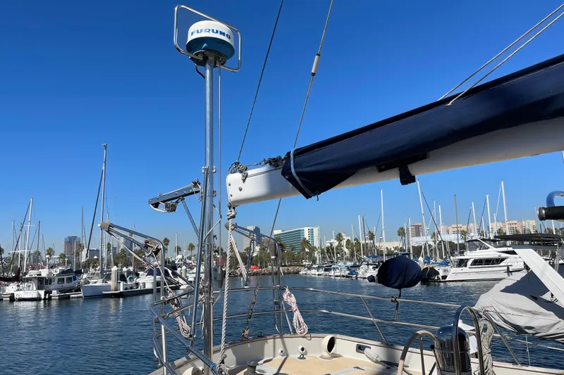 1978 Downeast 38 sailboat in marina, clear blue sky, masts, and cityscape background.