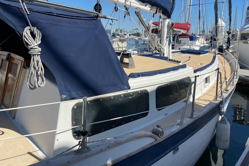 1978 Downeast 38 sailboat docked, featuring blue canvas covers and wooden accents.