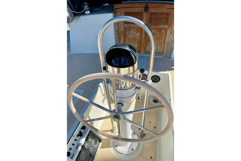 Steering wheel and compass of a 1978 Downeast 38 sailboat cockpit.