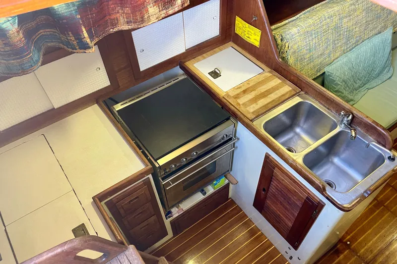 1978 Downeast 38 yacht kitchen with stove, double sink, and wooden cabinetry.