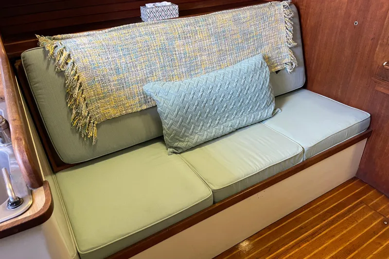 1978 Downeast 38 interior with cushioned seating, decorative throw, and wooden flooring.