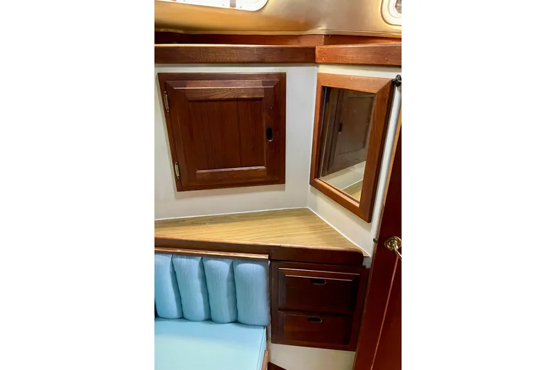 1978 Downeast 38 yacht interior with wooden cabinets and blue cushioned seating.