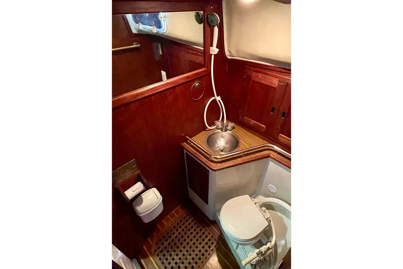 1978 Downeast 38 yacht bathroom with wooden cabinetry, sink, and toilet.