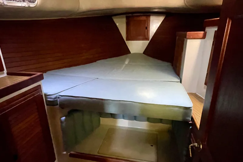 Cozy cabin interior of 1978 Downeast 38 sailboat with wooden accents and cushioned berth.