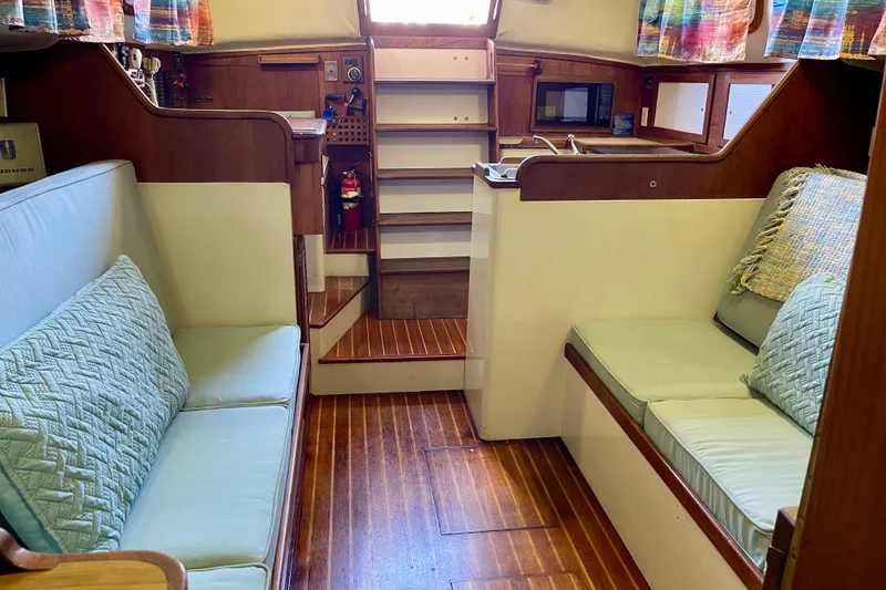 Interior of a 1978 Downeast 38 sailboat with cozy seating and wooden flooring.