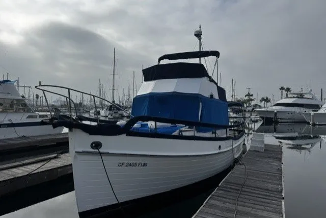 1974 Grand Banks 32 Sedan docked at marina under cloudy sky.