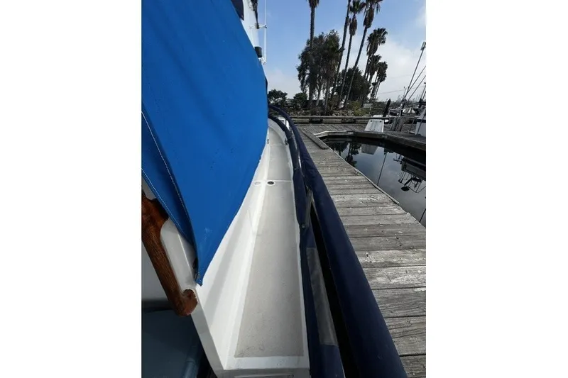 1974 Grand Banks 32 Sedan boat docked, featuring blue cover and wooden deck.