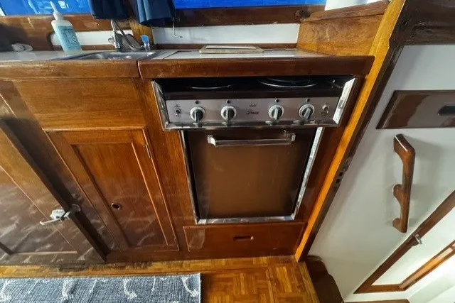 1974 Grand Banks 32 Sedan kitchen with wooden cabinetry and stove.