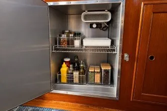 Storage cabinet on 1974 Grand Banks 32 Sedan with organized spices and condiments.