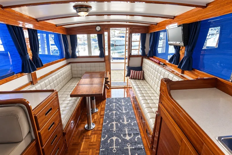 1974 Grand Banks 32 Sedan interior with wood finish, blue curtains, and white seating.