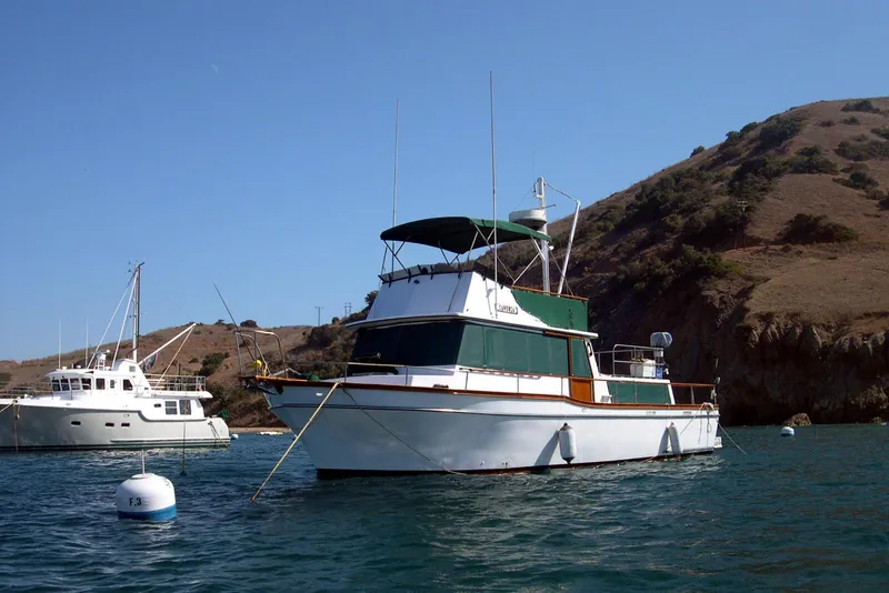 1978 Californian 42 LRC yacht anchored near a scenic coastal hillside.