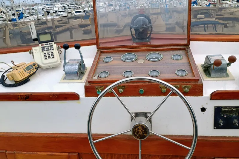 1978 Californian LRC boat helm with steering wheel, gauges, and communication devices in a marina.