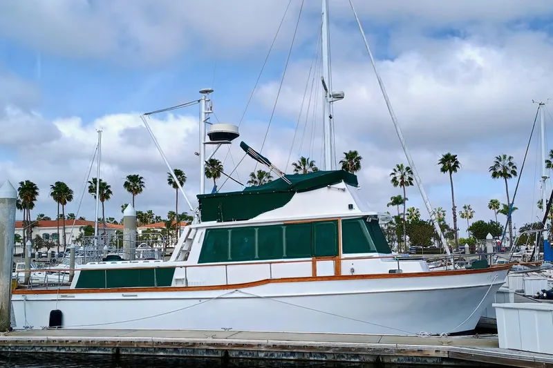 1978 Californian LRC yacht docked at marina with palm trees and cloudy sky.