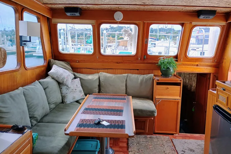 Cozy 1978 Californian LRC boat interior with green sofa, wooden table, and potted plant.
