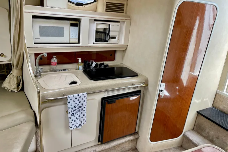Compact kitchen area in a 2000 Monterey 302 Cruiser boat, featuring a microwave and sink.