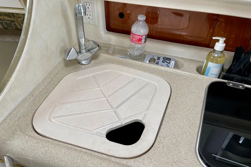 Kitchen sink area in a 2000 Monterey 302 Cruiser boat with faucet and countertop items.