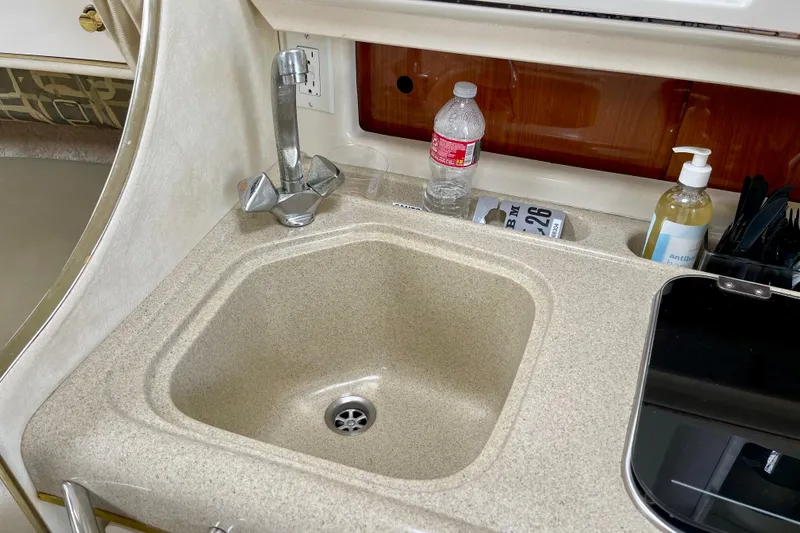 Kitchen sink area in a 2000 Monterey 302 Cruiser boat with faucet and countertop items.